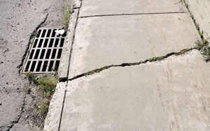 damaged sidewalk and drain due to deferred maintenance