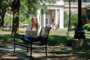 student on bench with laptop