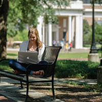 student on bench with laptop